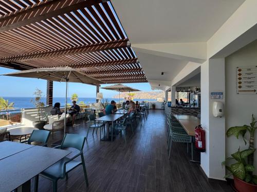 a restaurant with tables and chairs and a view of the ocean at Hotel Por Do Sol in Tarrafal