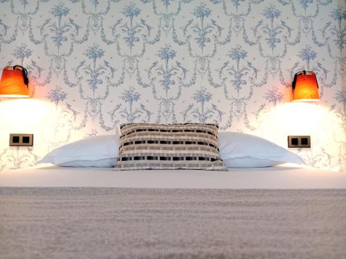 a bedroom with a bed with two lamps on the wall at Grand Hôtel de l'Europe - Morlaix Centre in Morlaix