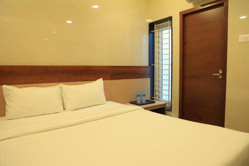 a bedroom with a white bed with a wooden headboard at TCS Residency in Kanchipuram