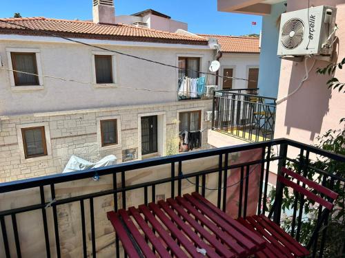 a red bench on a balcony with a building at Yeşim Pansiyon in Cesme
