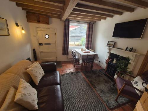 ein Wohnzimmer mit Sofa und Tisch in der Unterkunft Lime Kiln Quay Cottage in Woodbridge