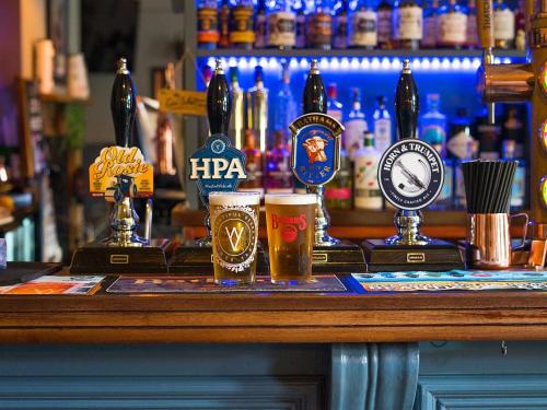 a bar with three glasses of beer on a counter at horn and trumpet in Bewdley