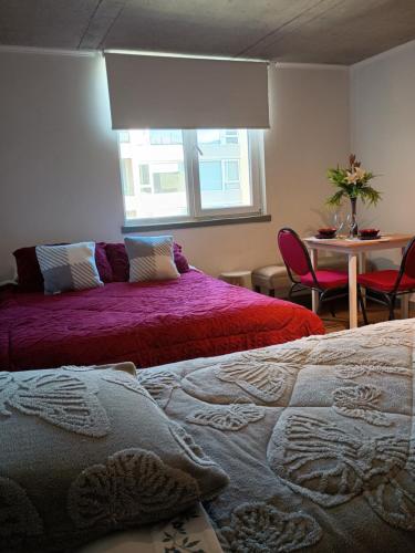 a bedroom with two beds and a table and a window at Departamento Barcelona in Temuco