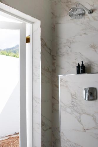 a bathroom with a shower with white marble walls at La Paris Estate in Franschhoek