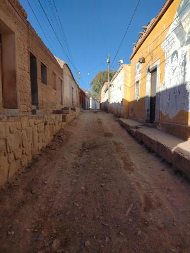 an empty dirt road in an alley between buildings at Casa La Candelaria in Tilcara