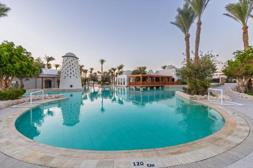 a large swimming pool in a resort with palm trees at Grand Makadi - Couples and Families Only in Hurghada