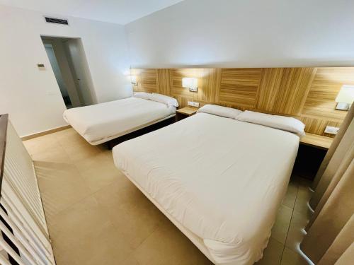 a hotel room with two beds and a desk at Apartaments Lauria in Tarragona