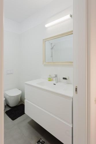 a white bathroom with a sink and a mirror at City Center Accommodation 103 in Reşiţa