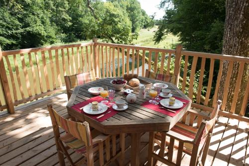 une table en bois avec de la nourriture sur une terrasse dans l'établissement Les Cabanes des Blots, à La Bussière