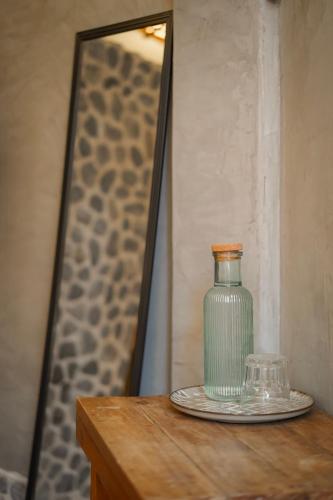 a glass bottle on a wooden table in front of a mirror at Eco Lodge Mancora in Máncora