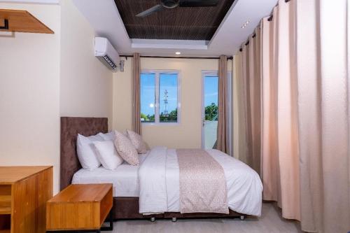 a bedroom with a bed and a large window at Fen Villa in Dharavandhoo