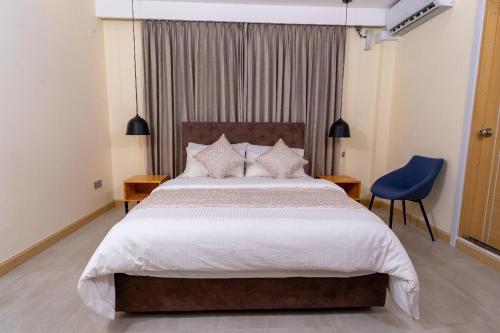 a bedroom with a large bed and a blue chair at Fen Villa in Dharavandhoo