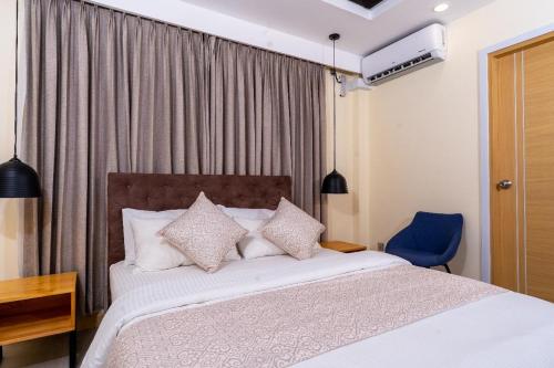 a bedroom with a bed and a blue chair at Fen Villa in Dharavandhoo