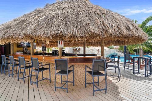 a bar with chairs and a large straw umbrella at The Ritz Hostel in Willemstad