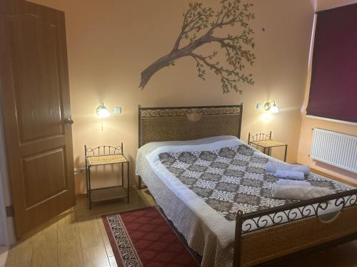 a bedroom with a bed and a tree on the wall at Klever-ok in Nerubayskoye