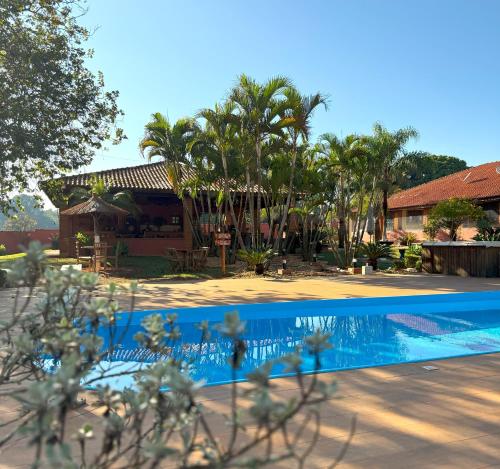 a swimming pool in front of a house with palm trees at Sítio CEL com Suítes aconchegantes em Boituva in Boituva