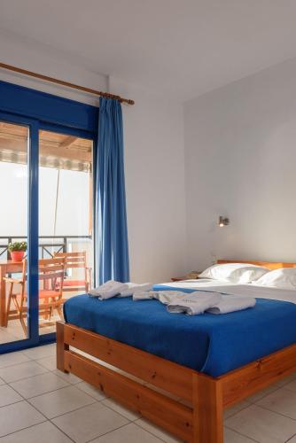 a bedroom with a bed with blue sheets and a balcony at Finikas Studios & Apartments - Kalamaki Holidays in Kalamaki