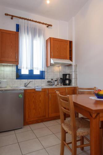 a kitchen with wooden cabinets and a wooden table with a wooden tableablish at Finikas Studios & Apartments - Kalamaki Holidays in Kalamaki
