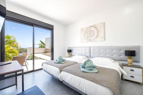 een witte slaapkamer met 2 bedden en een balkon bij villasroyale Silvermoon in San Bartolomé