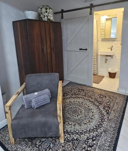 a living room with a chair and a bathroom at Upstairs R-4 Self Catering Unit in White River