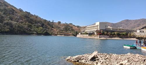 une rivière avec un bâtiment et un bateau dans l'eau dans l'établissement Hotel Kumbha Heritage, à Kelwāra