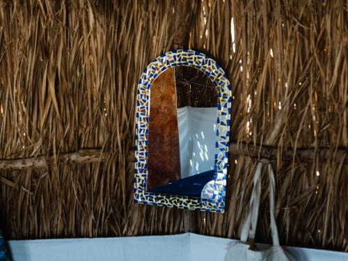 a mirror on a straw wall with a blue at Natural Lodge in Dahab
