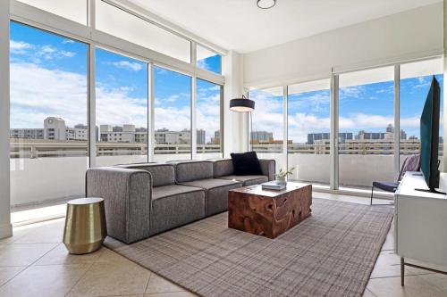 a living room with a couch and large windows at Roami at Sunny Isles in Miami Beach