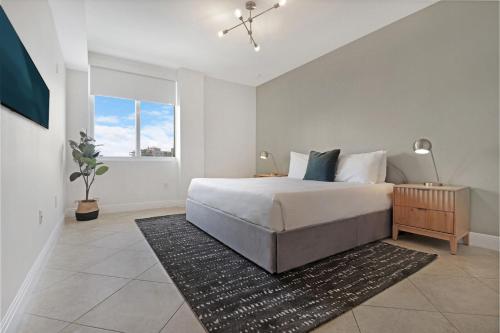 a white bedroom with a bed and a window at Roami at Sunny Isles in Miami Beach