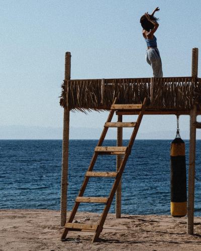a woman standing on top of a straw roof on the beach at Natural Lodge in Dahab