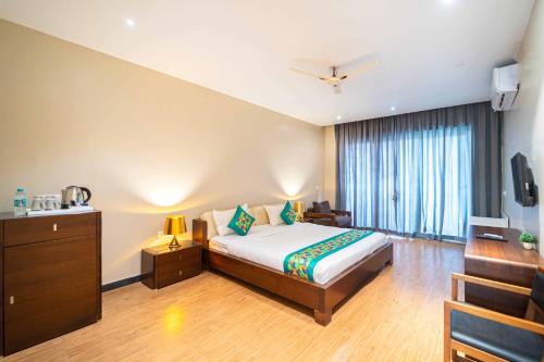 a hotel room with a bed and a television at Skazka beach resort in Mandrem