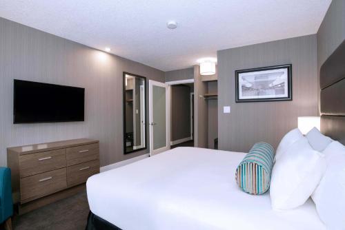 a bedroom with a white bed and a television at Sandman Signature Calgary Downtown Hotel in Calgary