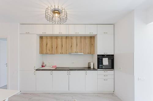 a kitchen with white cabinets and a chandelier at City Center Accommodation - 108 in Reşiţa