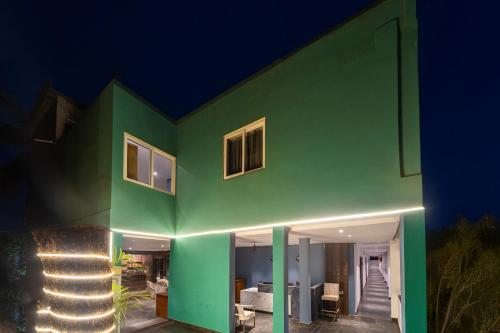 a green house with lights on it at night at Skazka beach resort in Mandrem