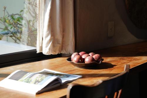a bowl of fruit on a wooden table with a book at Dechiu in Hoi An