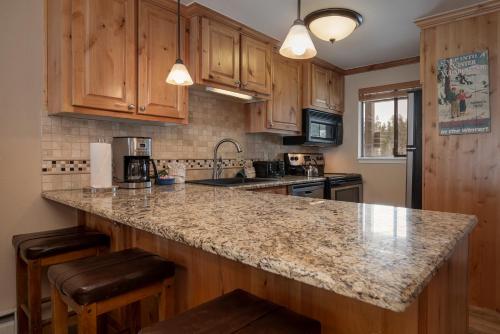 Una cocina con gabinetes de madera y encimera de granito. en Beaver Village Unit #0412, en Winter Park