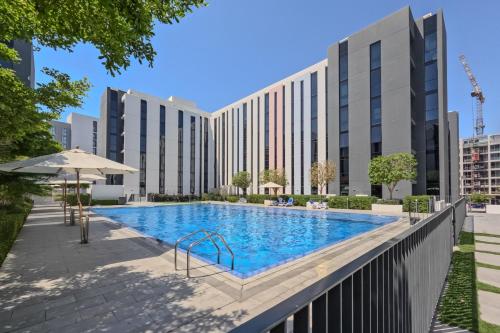 a swimming pool in front of a building at 2BR Aljada Apartment - 3 Washrooms - Sleeps 6 - Boulevard in Sharjah