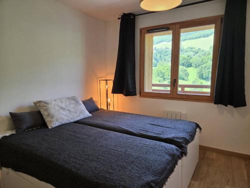 ein Schlafzimmer mit einem großen Bett mit Fenster in der Unterkunft Neuf T2 avec balcon, parking et casier à skis, idéal pour 4 personnes - FR-1-291-1021 in Valmorel