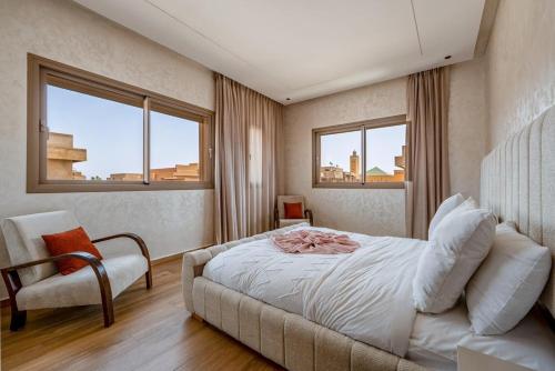 a bedroom with a bed and a chair and two windows at Villa Lina in Marrakech