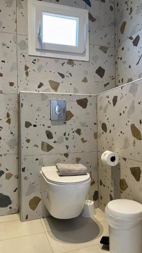 a bathroom with a toilet and a window on the wall at Palma Village by Greek Pride Hotels in Skála Foúrkas