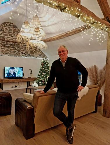 a man standing in a living room with a christmas tree at Au Cœur des Vallées in Couvin