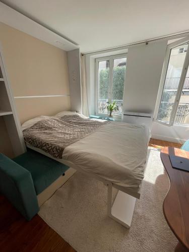 um pequeno quarto com uma cama e uma janela em Studio Cosy au charme Parisien - Butte aux cailles em Paris