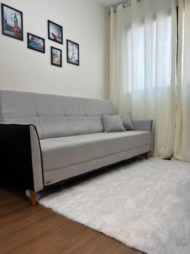 a gray couch in a living room with a window at 2 Quartos c Ar, Wi-Fi e conforto perto de tudo in Maringá