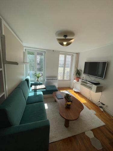 uma sala de estar com um sofá verde e uma mesa de centro em Studio Cosy au charme Parisien - Butte aux cailles em Paris