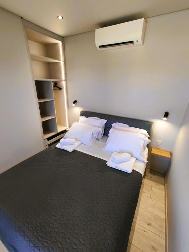 a bedroom with a black bed with white pillows at LIViT Condo Elafonisi in Agios Padeleimon
