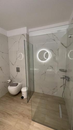 a bathroom with a toilet and a glass shower stall at Palma Village by Greek Pride Hotels in Skála Foúrkas