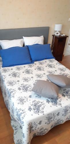 un lit avec des draps et des oreillers bleus et blancs dans l'établissement Résidence les Rossignols, à Neuilly-lès-Dijon