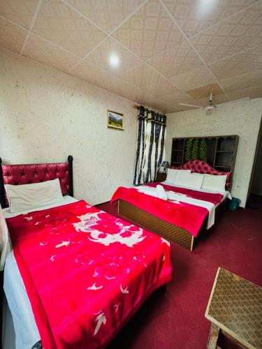 two beds in a room with red sheets at Skardu Baltistan Village Guest House in Skardu