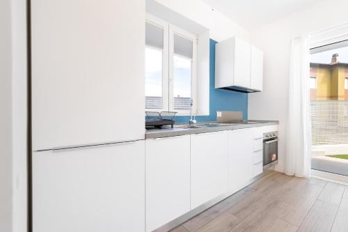 Una cocina blanca con gabinetes blancos y un fregadero. en Hostdomus-La casa degli artisti-Michelangelo-Giotto-Raffaello, en Andora