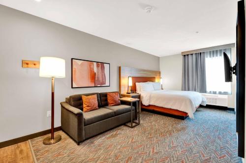 a hotel room with a bed and a couch at Candlewood Suites - Detroit - Auburn Hills by IHG in Auburn Hills