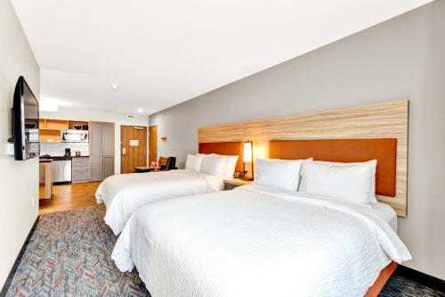 a hotel room with two beds and a kitchen at Candlewood Suites - Detroit - Auburn Hills by IHG in Auburn Hills
